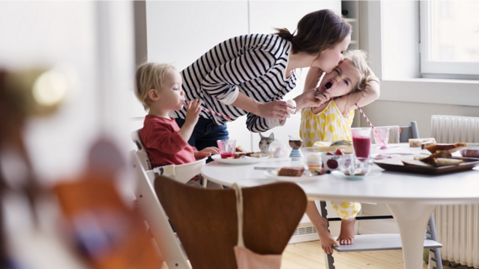 Dos niños comiendo con su madre