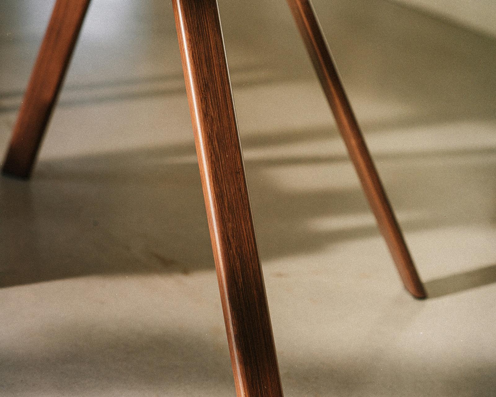 Primo piano delle gambe in legno marrone scuro di una sedia Tripp Trapp su un pavimento chiaro.