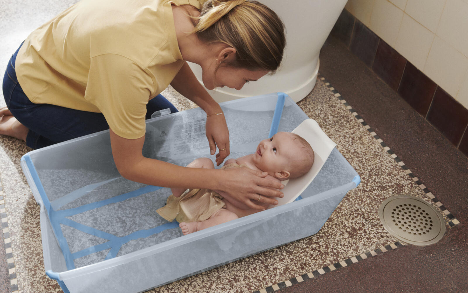 Mother bathing newborn baby in stokke flexi bath XL with newborn support.