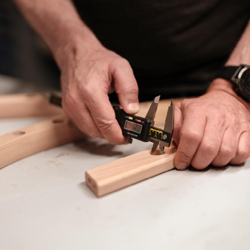 Product development designer measuring a wooden Stokke product.
