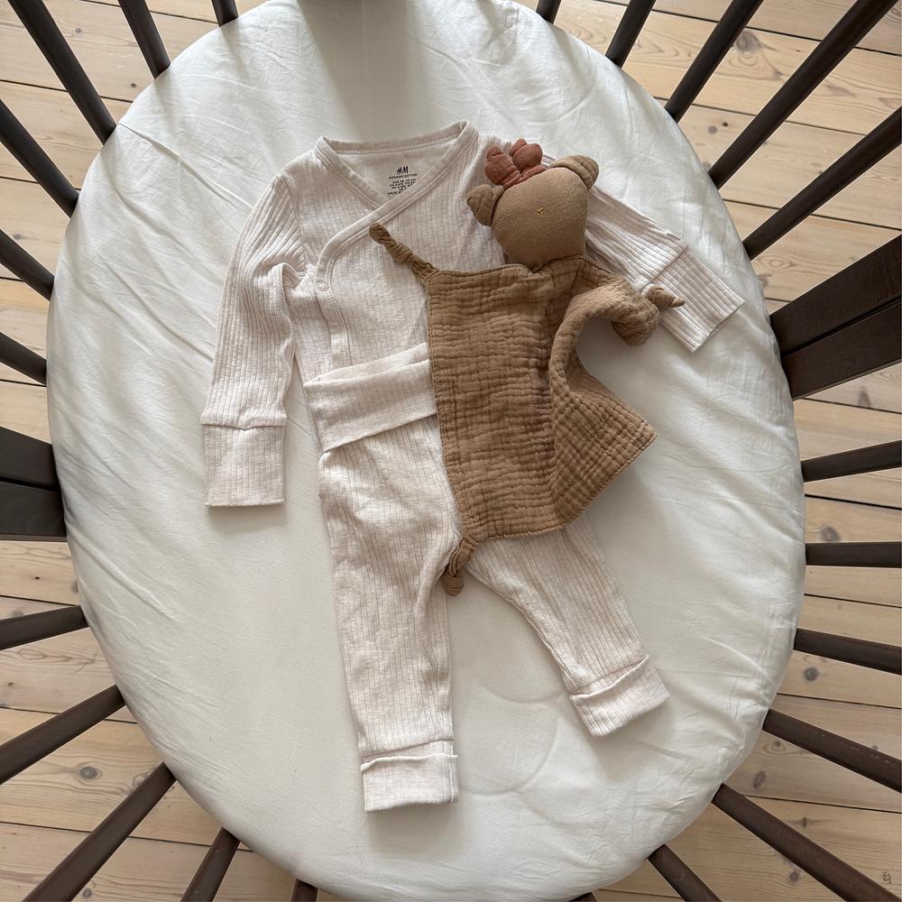 Baby clothes in sleepi mini bed.