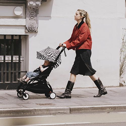 Eine Mutter geht mit einem YOYO-Kinderwagen im Zebramuster spazieren.