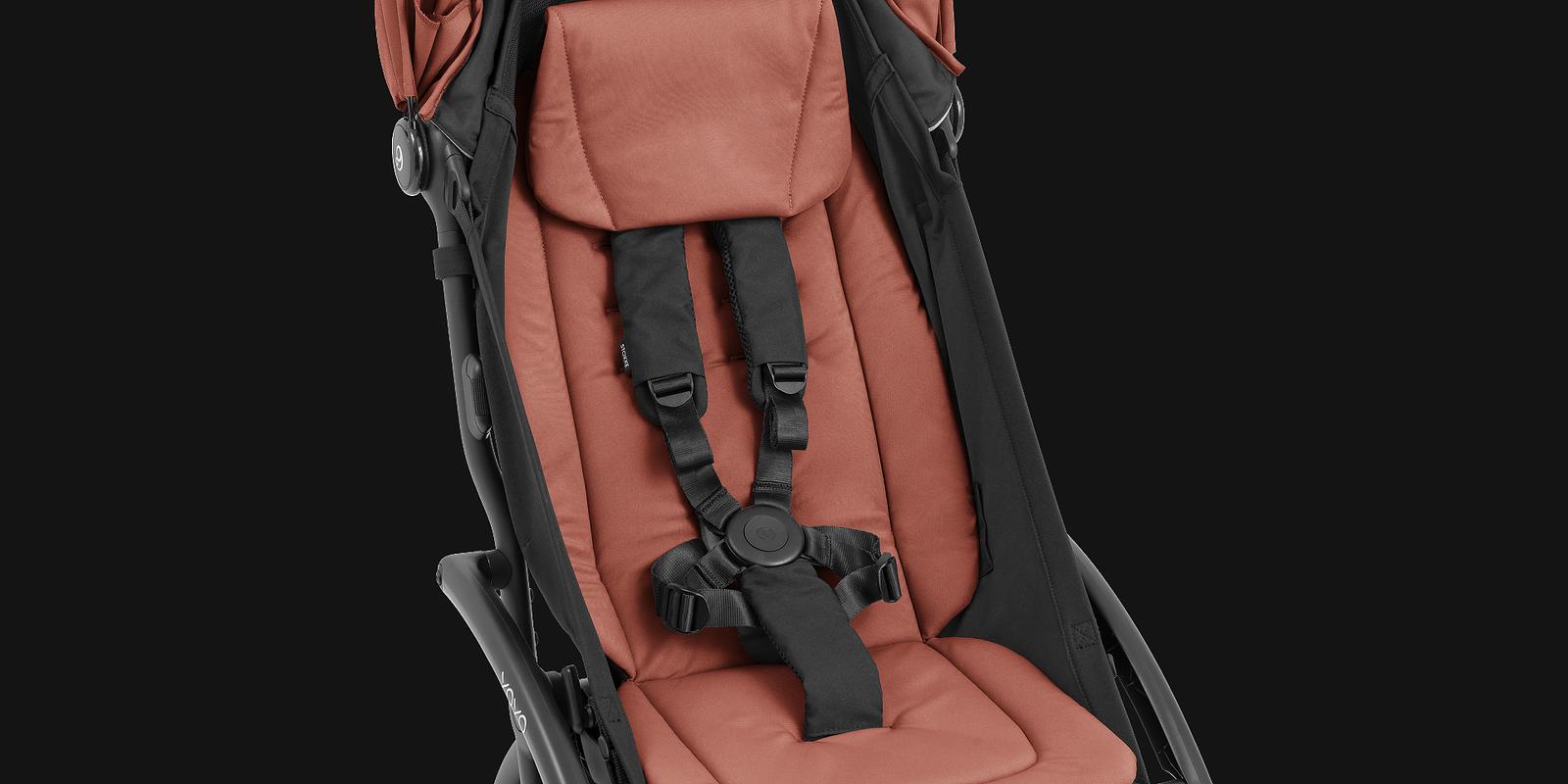 Närbild av en STOKKE YOYO barnvagnsits i terrakotta med en svart 5-punktssele.