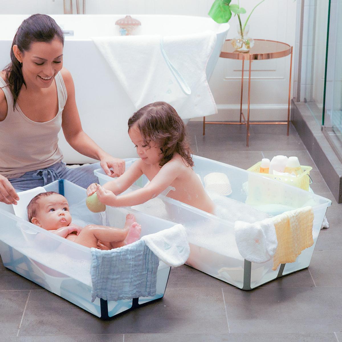 A great baby gift is the stokke flexi bath which comes in two sizes. A mother bathing her newborn baby and young toddler.