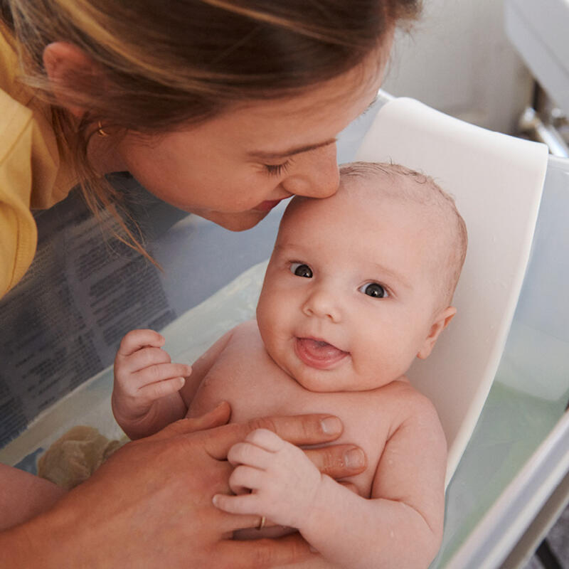 A mother cleaning her baby in Flexi bath with newborn support.