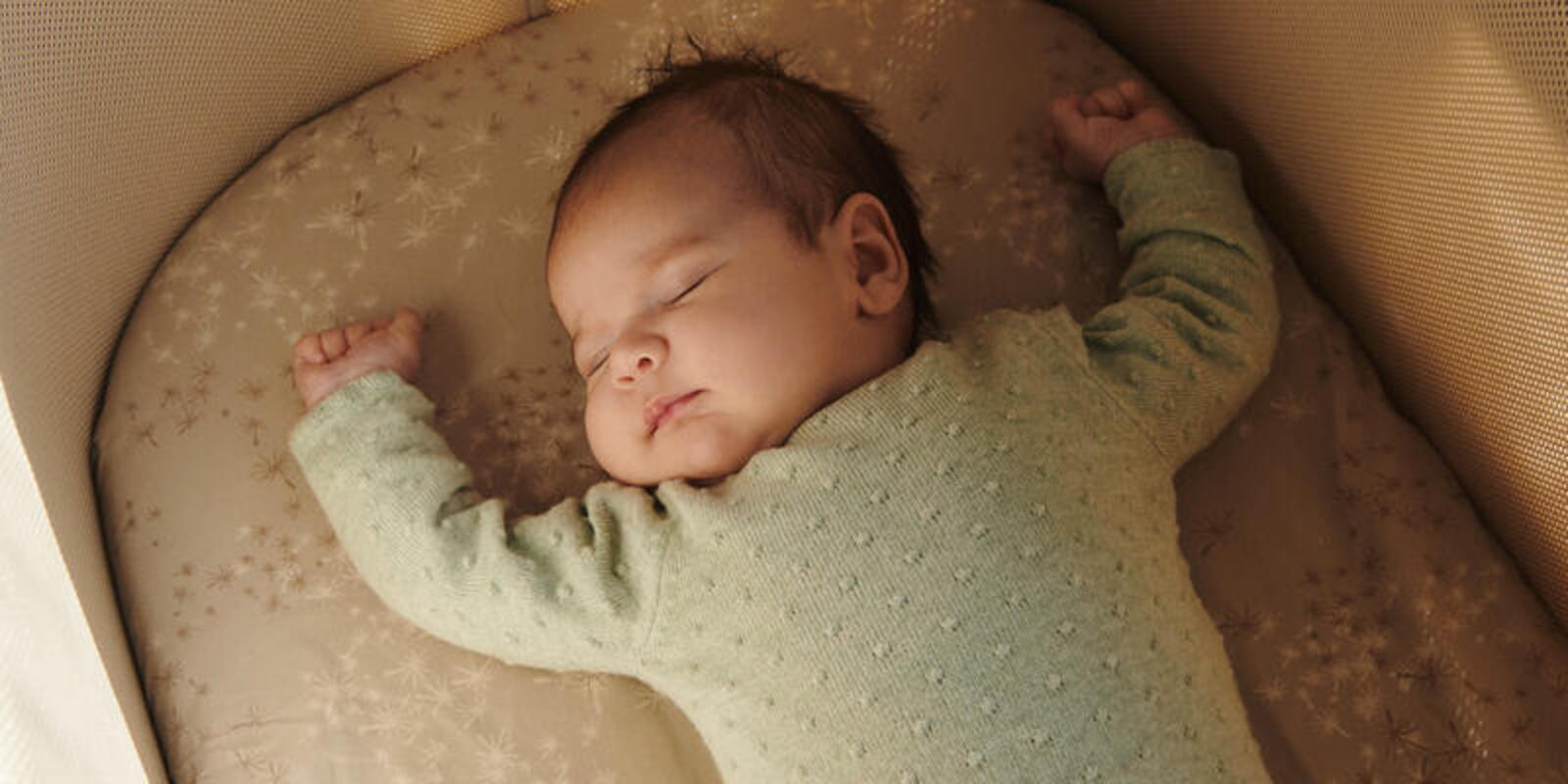 Baby sleeping in snoozi bassinet.