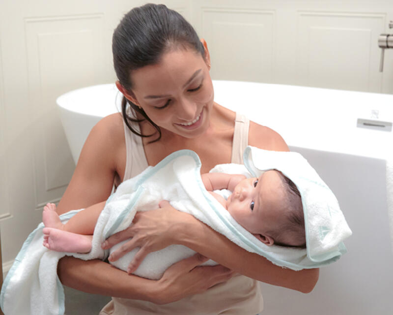 Mother holding her child in a blanket after a bath.