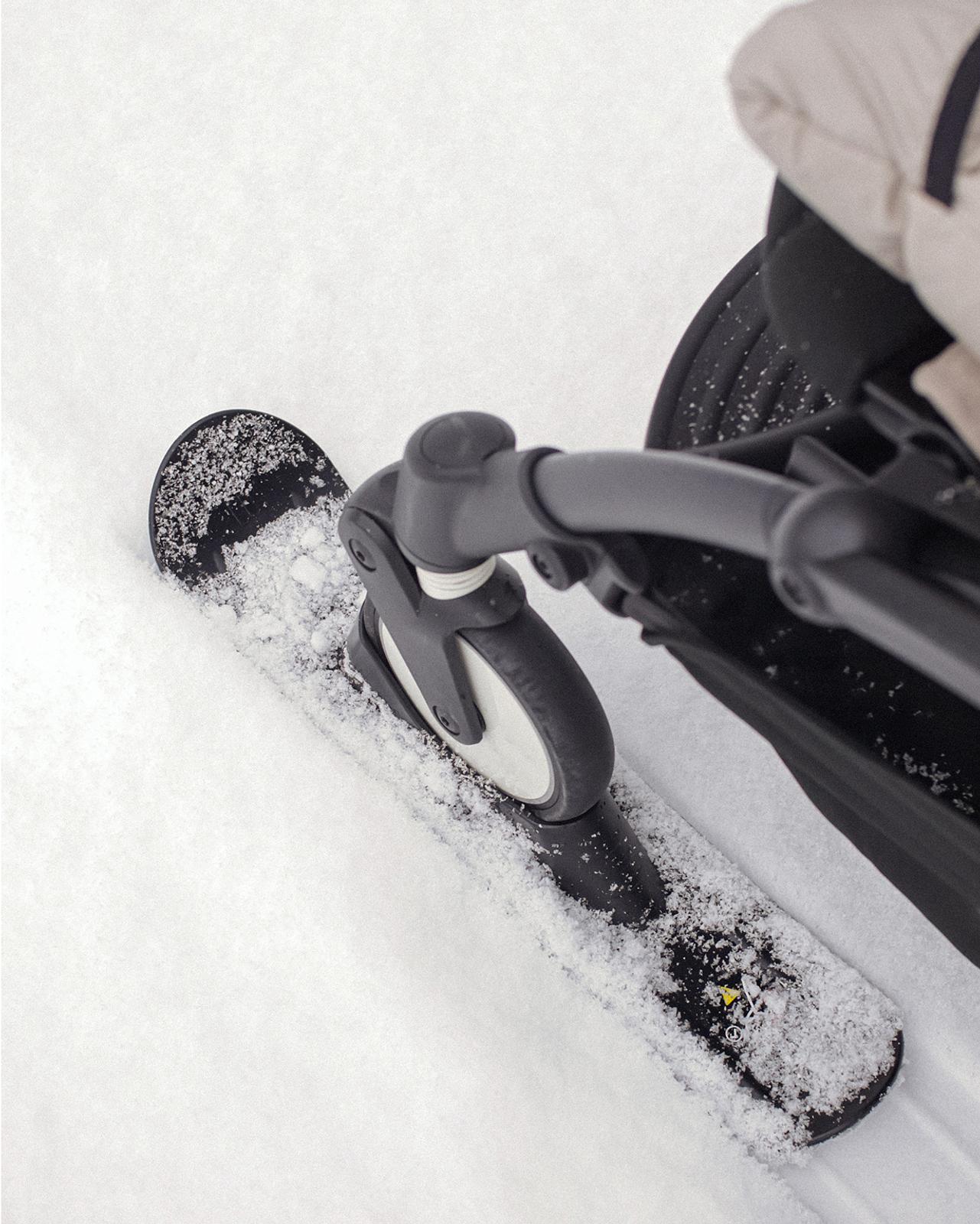 STOKKE YOYO stroller with a ski attachment glides through fresh snow.