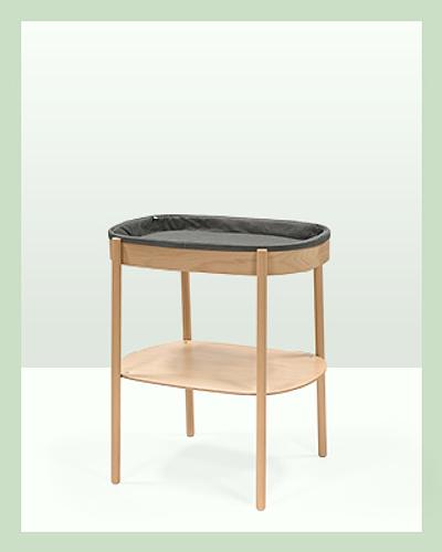 A sleepi changing table in an oval shape in color natural with grey cushioned changing pad.