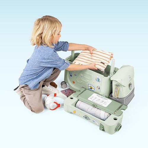 A child is packing up his ride-on luggage with clothes.​