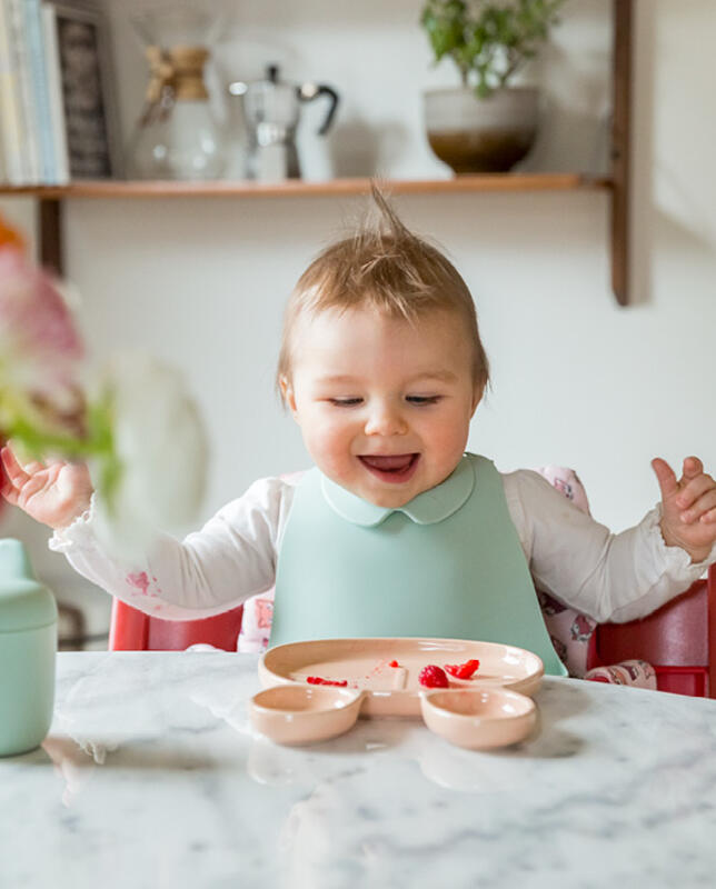 Bambino che mangia seduto sulla sedia Tripp Trapp