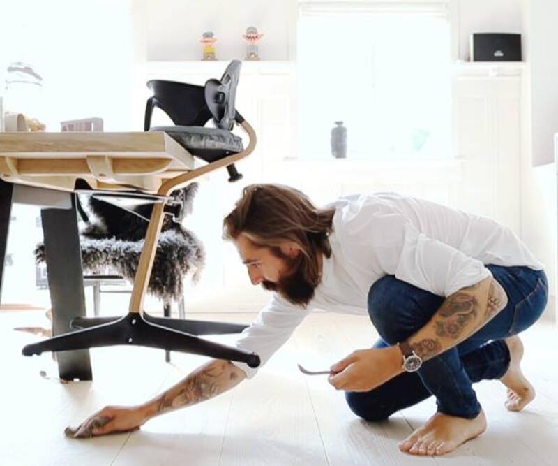 Stokke Stokke® Nomi® with baby set hanging from the kitchen chair as Dad cleans the floor underneath. 