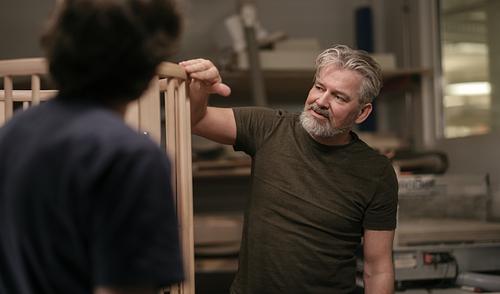 A craftman touching a wooden children's bed.