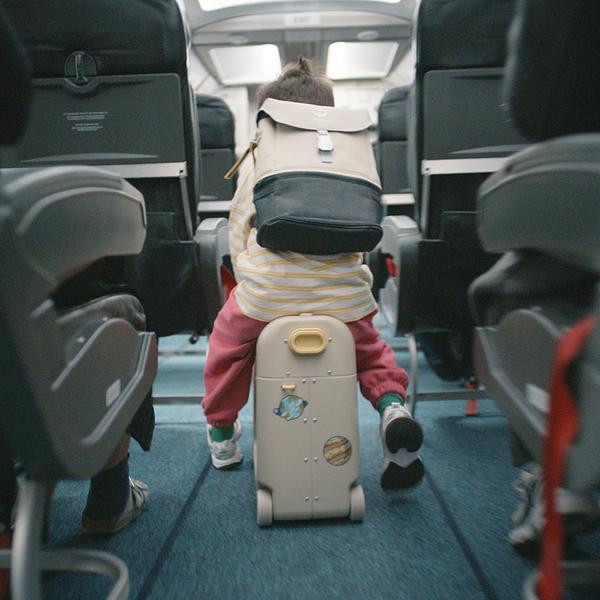 Child riding Jetkids bedbox in plane aisle.