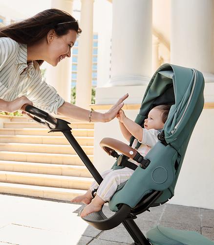 Mother and child high fiving while baby is in Xplory stroller.