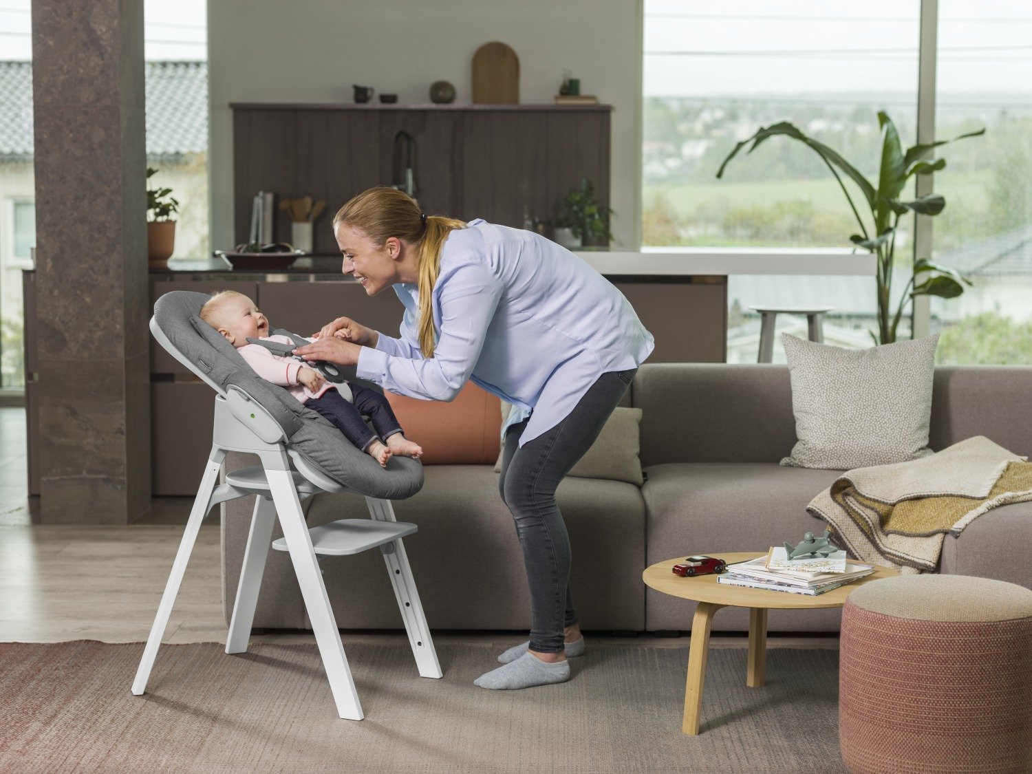 Stokke&reg; Steps&trade; high chair Oak White with Light Grey seat and Bouncer in Deep Grey textile. On the chair.